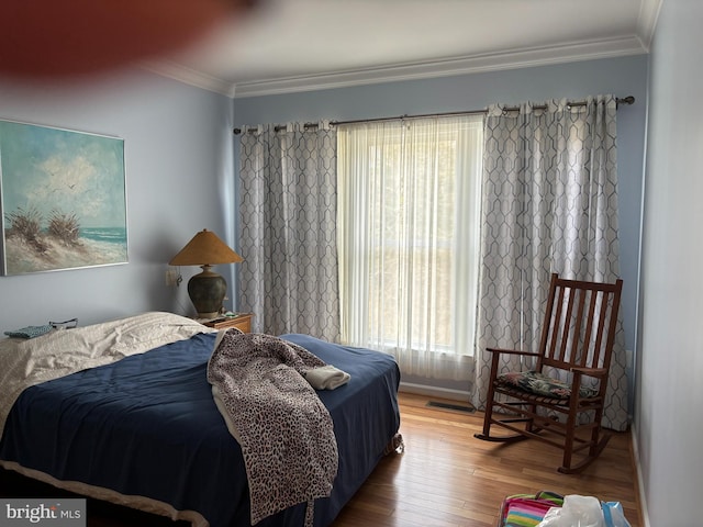 bedroom featuring visible vents, crown molding, baseboards, and wood finished floors