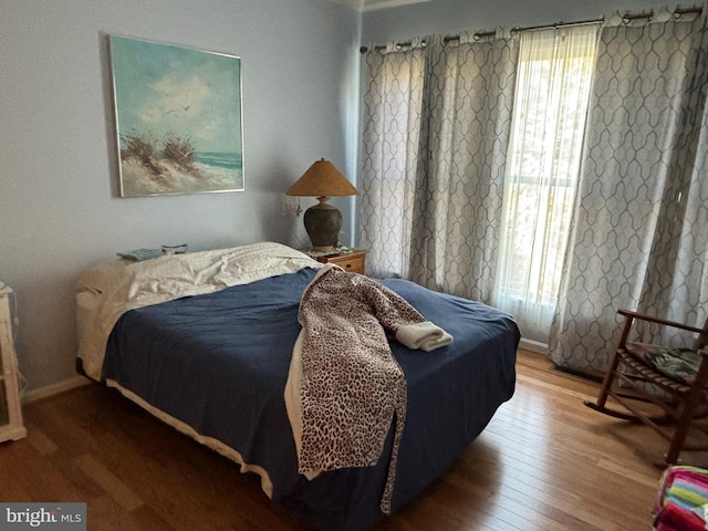 bedroom featuring multiple windows, wood finished floors, and baseboards