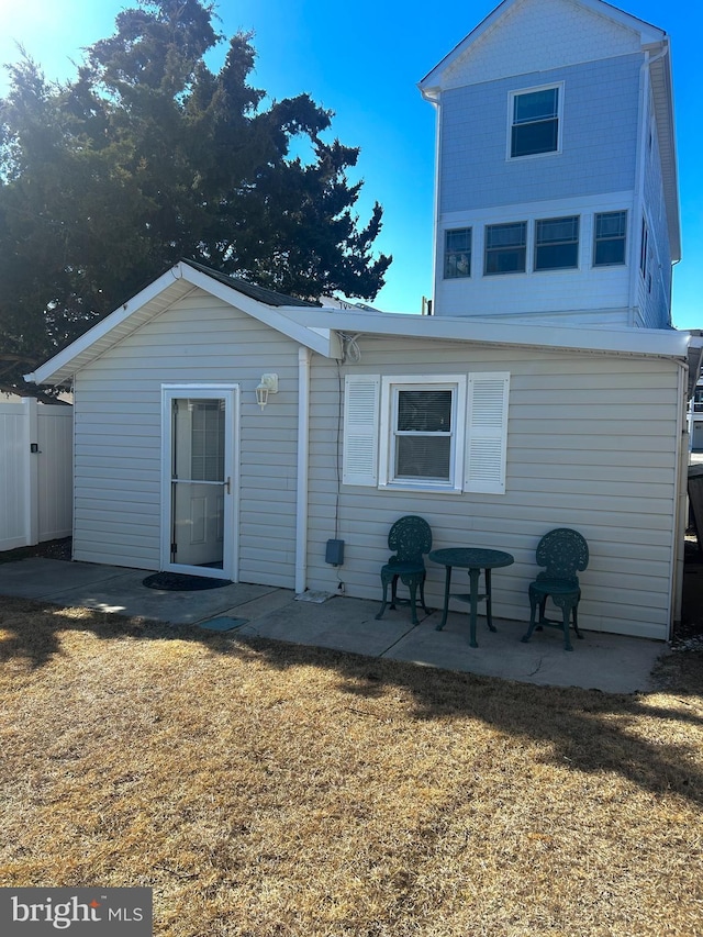 rear view of property with a patio, a lawn, and fence