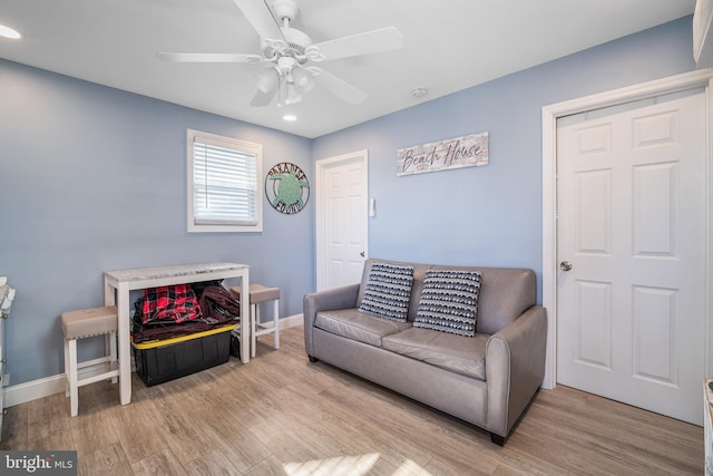 living area featuring baseboards, a ceiling fan, and wood finished floors