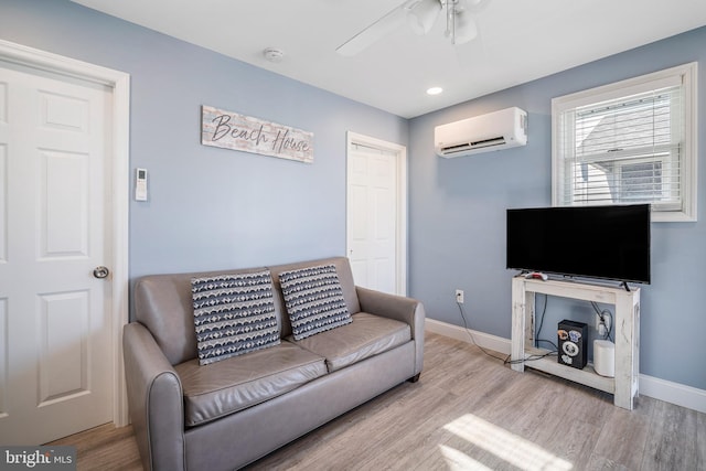 living area featuring baseboards, an AC wall unit, and wood finished floors