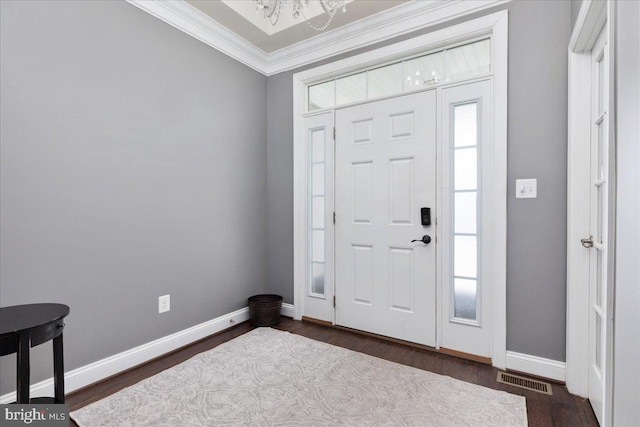 foyer featuring a notable chandelier, dark wood-type flooring, visible vents, baseboards, and ornamental molding