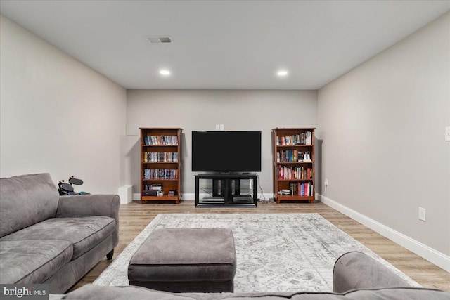 living room featuring visible vents, baseboards, wood finished floors, and recessed lighting