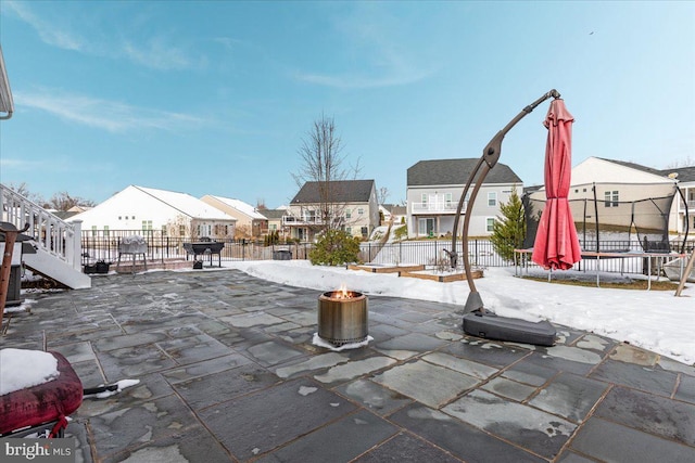 snow covered patio featuring fence private yard, a trampoline, and a residential view