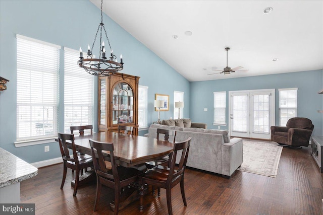 dining space featuring ceiling fan with notable chandelier, plenty of natural light, dark wood finished floors, and baseboards