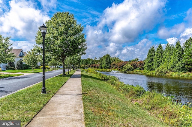 view of street with curbs, street lighting, a water view, and sidewalks