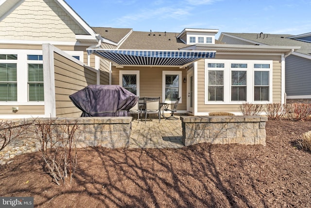 back of property featuring roof with shingles and a patio