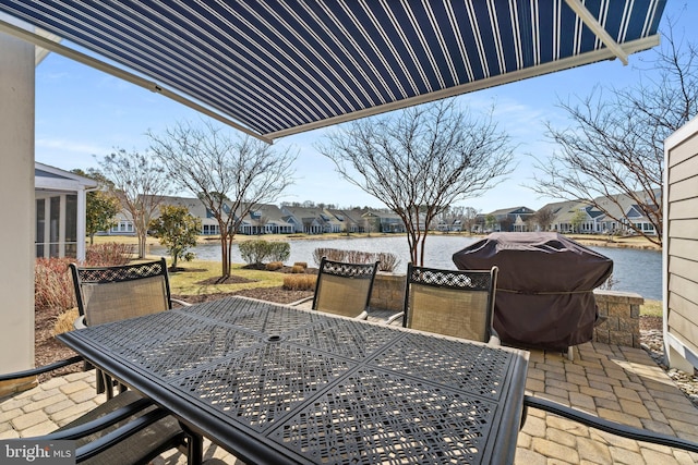 view of patio with a water view, a residential view, area for grilling, and outdoor dining space