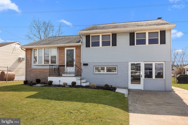 split level home with a shingled roof, fence, stucco siding, a front lawn, and heating fuel