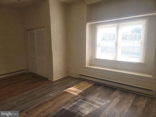 unfurnished room with a baseboard radiator, dark wood finished floors, and baseboards