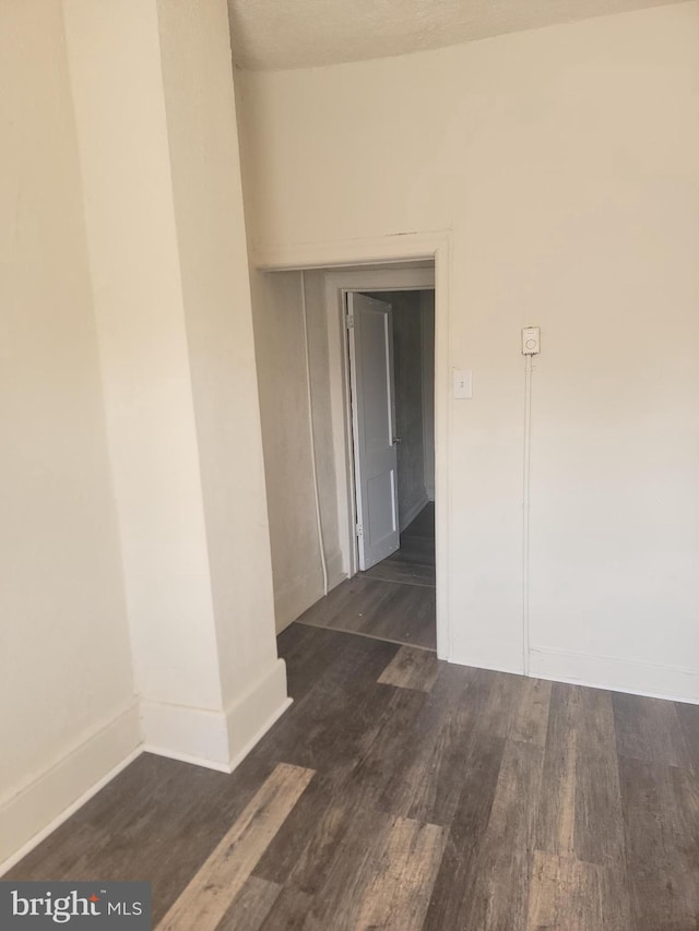 spare room featuring baseboards and wood finished floors