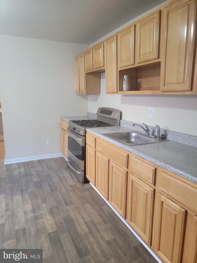 kitchen featuring gas range, dark wood-style flooring, light countertops, light brown cabinetry, and a sink