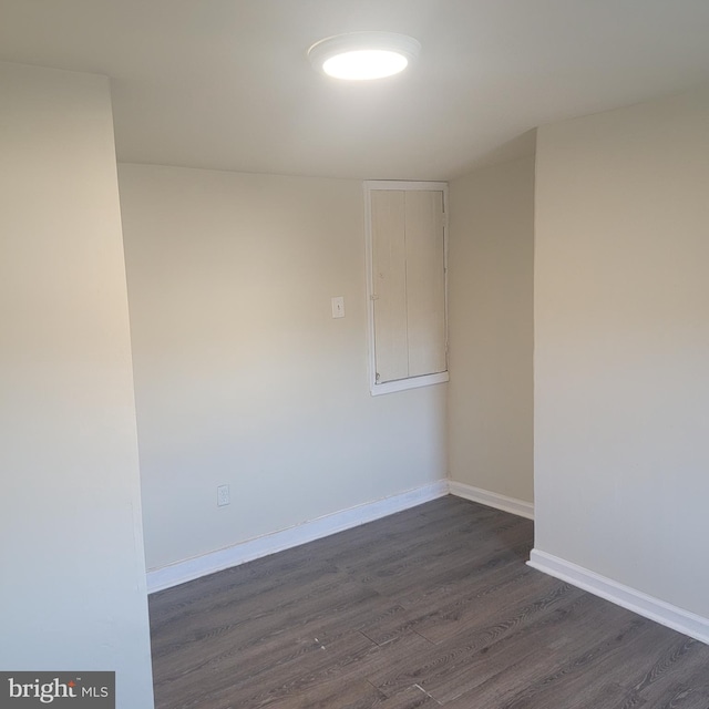 empty room featuring dark wood-style floors and baseboards