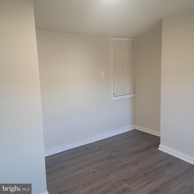 empty room with baseboards and dark wood-type flooring