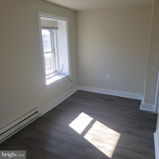 empty room with dark wood-style flooring, baseboard heating, and baseboards