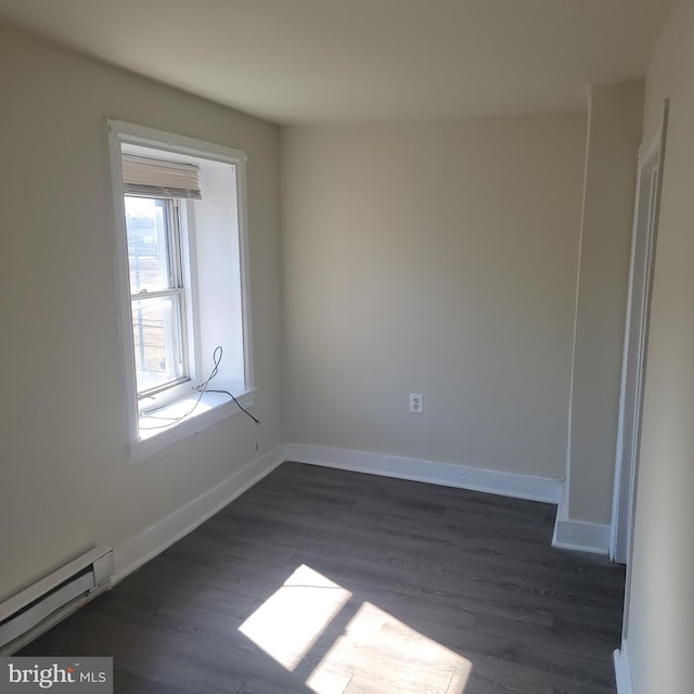 empty room with a baseboard radiator, dark wood finished floors, and baseboards