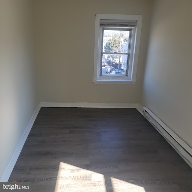 empty room with a baseboard radiator, baseboards, and dark wood finished floors