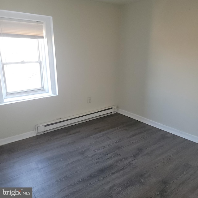 spare room featuring dark wood-type flooring, a baseboard radiator, and baseboards