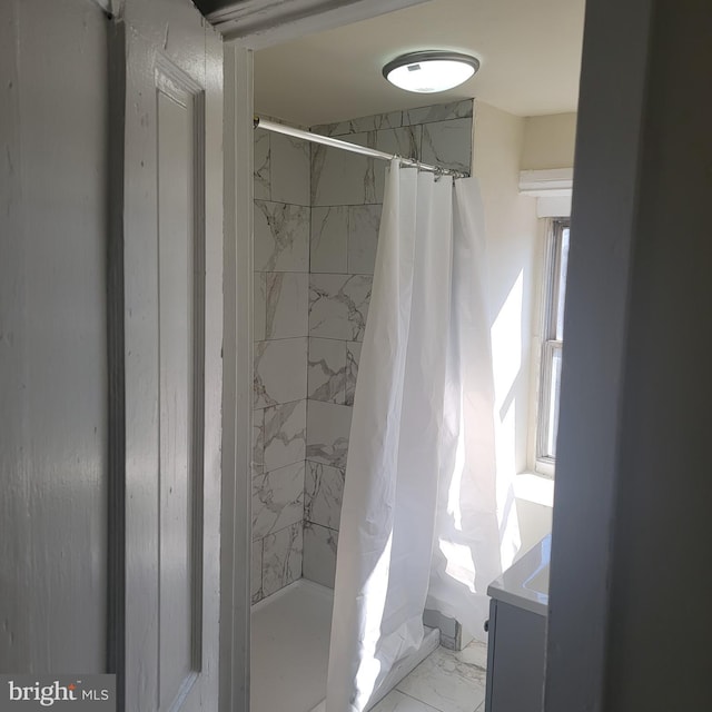 bathroom featuring marble finish floor and a stall shower