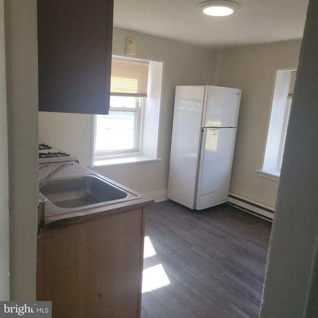 kitchen with dark wood-style floors, a baseboard radiator, a sink, and freestanding refrigerator