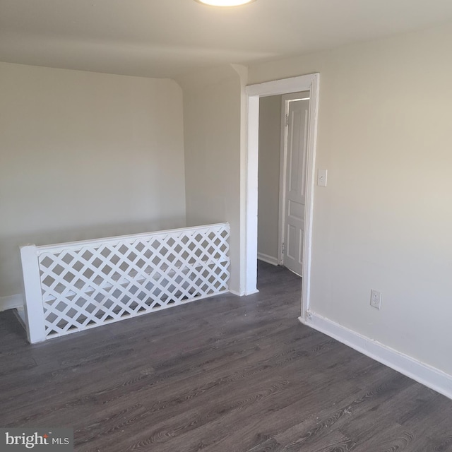 empty room with dark wood-type flooring and baseboards