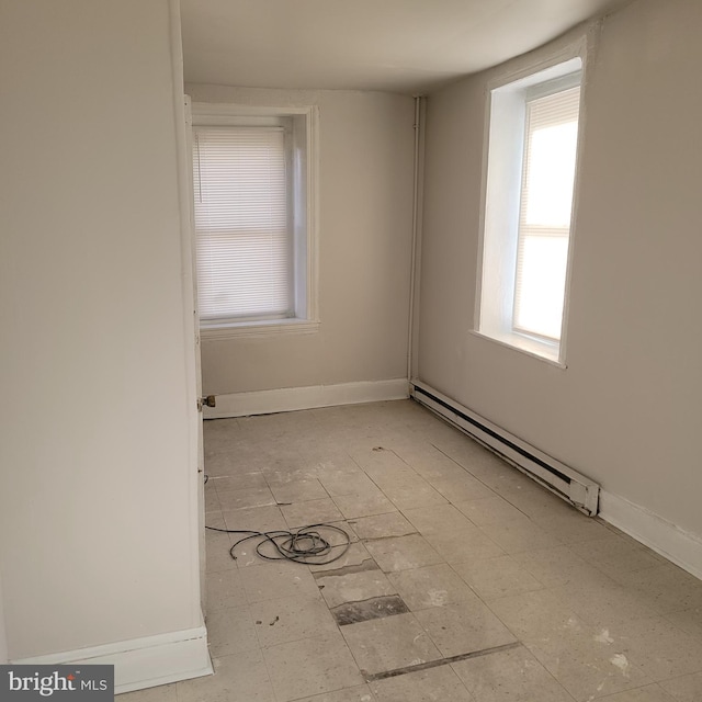 unfurnished room featuring a baseboard heating unit and baseboards