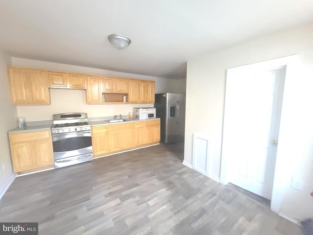 kitchen featuring light brown cabinets, dark wood-style flooring, a sink, light countertops, and appliances with stainless steel finishes