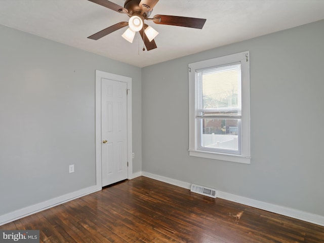 empty room featuring hardwood / wood-style flooring, baseboards, visible vents, and ceiling fan