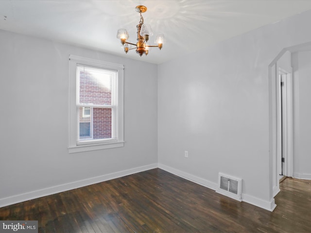 empty room with a chandelier, baseboards, visible vents, and dark wood-type flooring