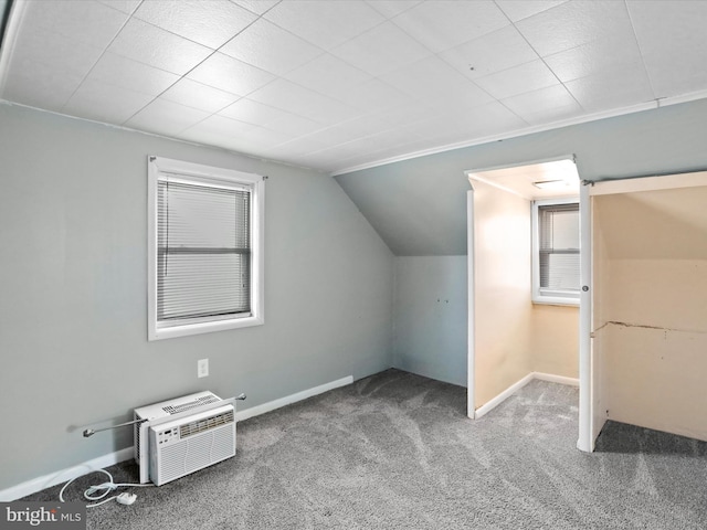 additional living space featuring a wall unit AC, carpet flooring, vaulted ceiling, and baseboards