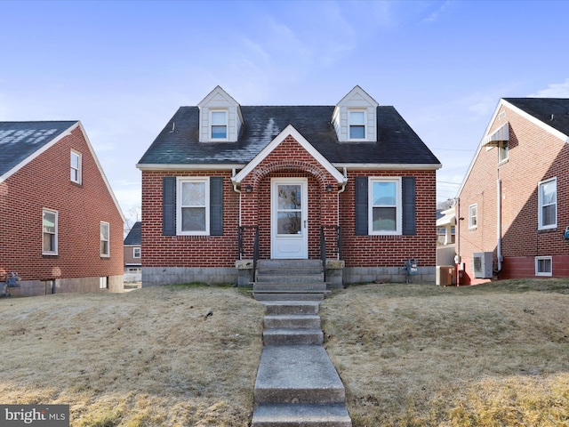 new england style home with brick siding, roof with shingles, and central AC unit