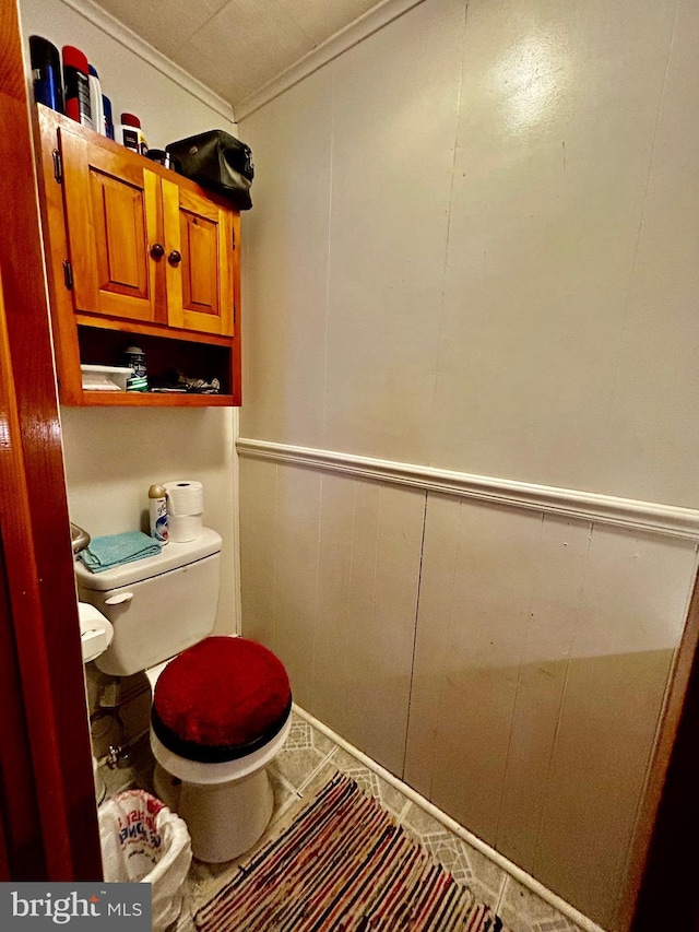 bathroom featuring ornamental molding, a wainscoted wall, and toilet