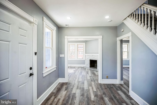 foyer with baseboards, dark wood-type flooring, a high end fireplace, and a healthy amount of sunlight