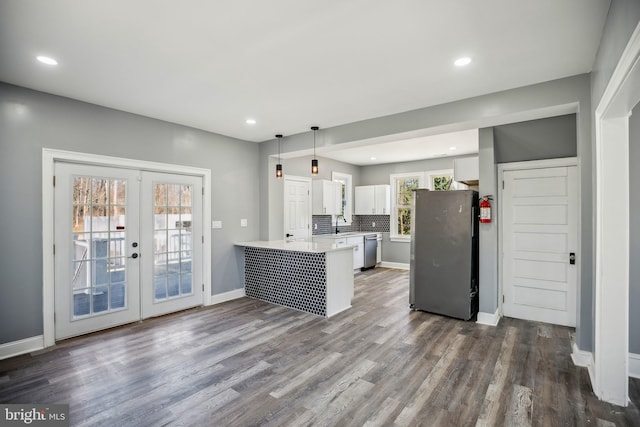 kitchen with stainless steel appliances, a peninsula, white cabinetry, light countertops, and pendant lighting