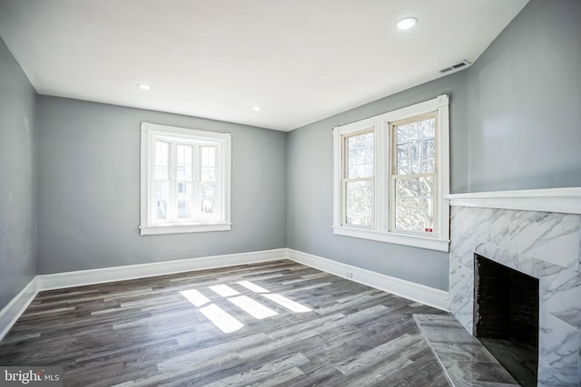 unfurnished living room with baseboards, a fireplace, visible vents, and a healthy amount of sunlight