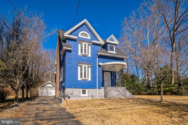 view of front of property with roof with shingles, a detached garage, a front lawn, and an outdoor structure