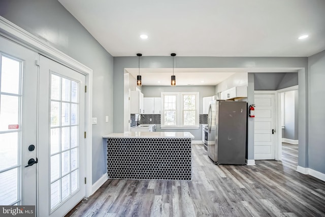 kitchen with a peninsula, a sink, white cabinetry, light countertops, and freestanding refrigerator