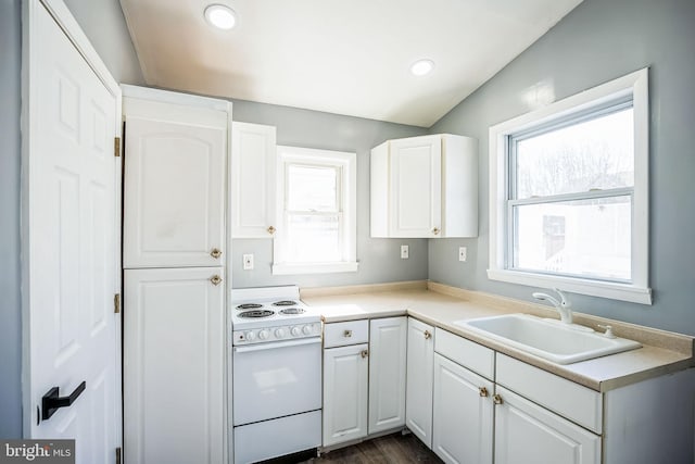 kitchen featuring electric stove, light countertops, a sink, and white cabinetry