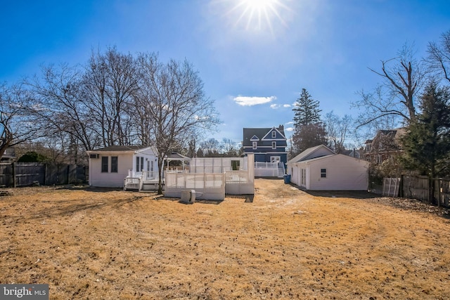 rear view of house featuring an outbuilding and fence