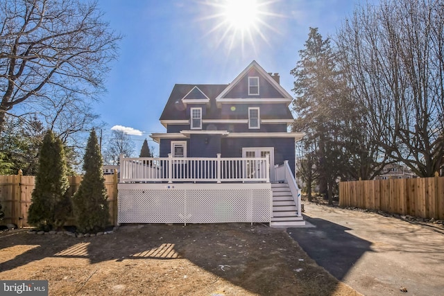 view of front of house with a chimney, fence, a deck, and stairs