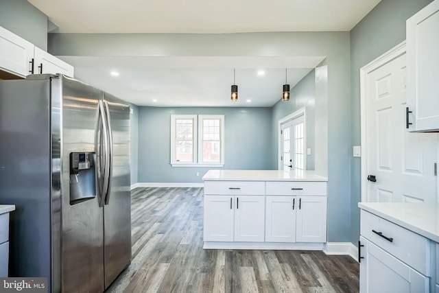 kitchen with white cabinets, a peninsula, light countertops, stainless steel refrigerator with ice dispenser, and pendant lighting