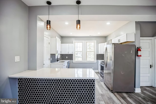 kitchen with a peninsula, white cabinetry, stainless steel appliances, and light countertops