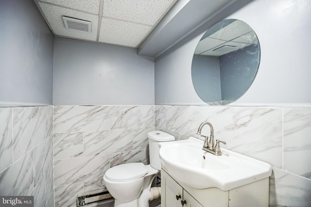 bathroom featuring visible vents, toilet, vanity, and a drop ceiling