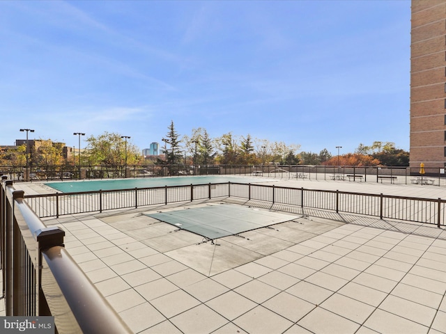 view of patio with a community pool and fence