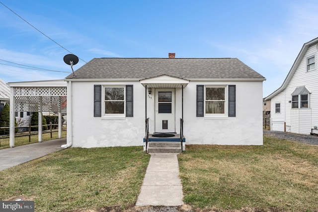 bungalow-style home with roof with shingles, a front yard, and stucco siding