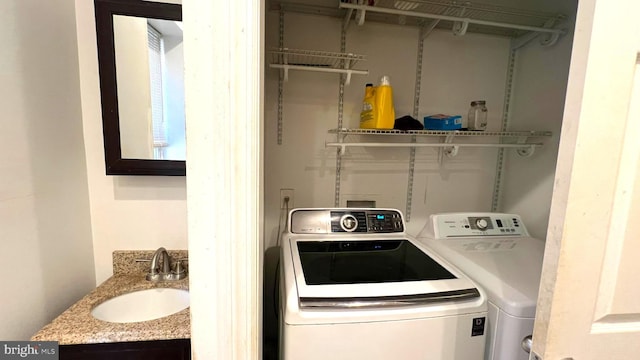 washroom featuring laundry area, washer and clothes dryer, and a sink