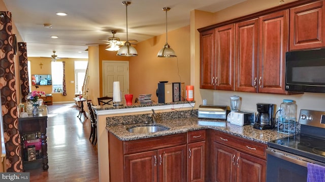 kitchen featuring black microwave, a peninsula, a sink, hanging light fixtures, and stainless steel range with electric stovetop