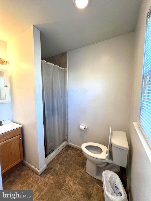 full bath featuring toilet, a shower stall, baseboards, and vanity