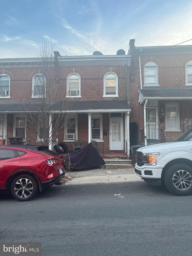 multi unit property featuring covered porch and brick siding