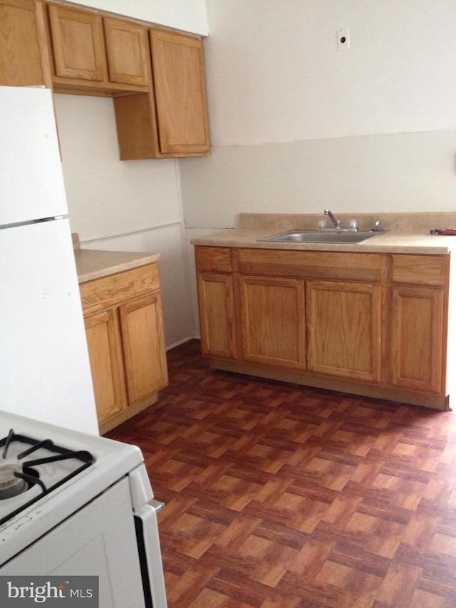 kitchen with light countertops, white appliances, and a sink